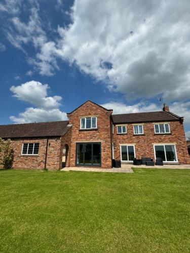 a brick house with a green lawn in front of it at Boundary Farm in Middleton
