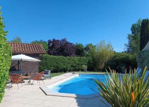 - une piscine dans un jardin avec des chaises et une table dans l'établissement Villa 150 m2 Bordeaux Océan Porte du Médoc, à Saint-Aubin-de-Médoc