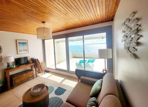 un salon avec un canapé et une vue sur l'océan dans l'établissement Studio les pieds dans l'eau et Parking, à Concarneau