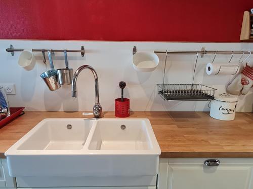 - une cuisine avec un évier blanc et un mur rouge dans l'établissement l'oasis girondine 4 étoiles, à Izon