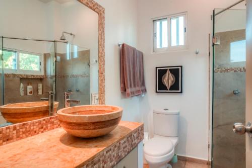 a bathroom with a wooden bowl sink and a toilet at Casa Gracias in Punta Mita