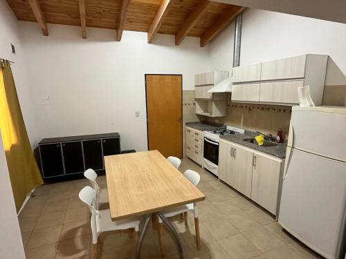 a kitchen with a wooden table and white appliances at Refugio Andino 2 in Malargüe