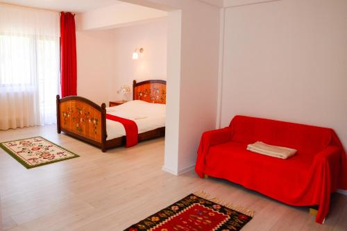 a bedroom with a bed and a red couch at Pensiunea Fish Valley in Cîmpu lui Neag