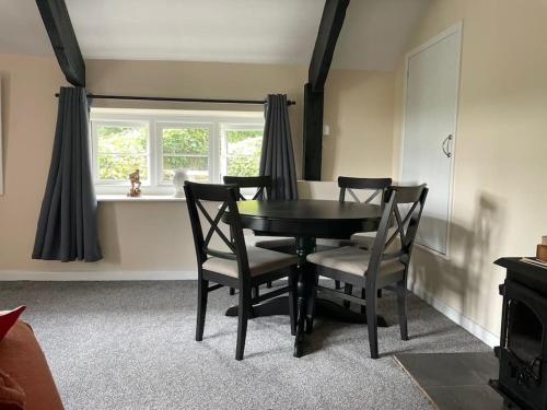 a dining room with a black table and chairs at The Cottage in Ashburton