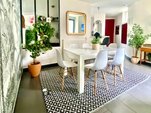une salle à manger avec une table et des chaises blanches dans l'établissement LESPARISNORMANDS - le duplex de la reine, proche Parc des expositions porte de Versailles et Tour Eiffel, à Boulogne-Billancourt