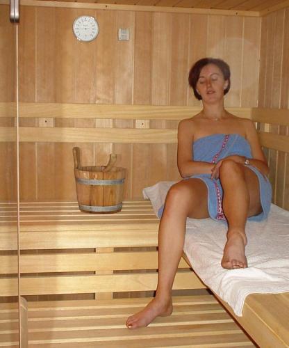 a woman sitting on a bed in a sauna at Gästehaus Waldruh in Gerlos