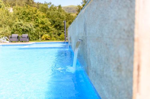 a pool with water pouring out of a wall at Gerês Country Stays - Quinta dos Motas in Ventosa