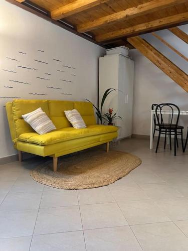 a yellow couch in a living room with a table at Casa Ondea in Marina di Pisa