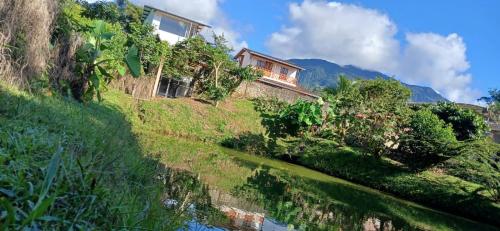 a house on a hill next to a body of water at Birdsong lodge in Mocoa