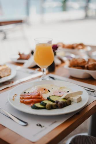 a plate of food on a table with a glass of orange juice at Noemie Hotel in Himare