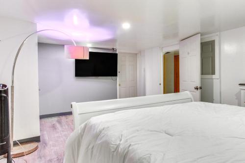 a white bedroom with a bed and a flat screen tv at Convenient Apt 2 Mi to Sprain Ridge Park! in Yonkers