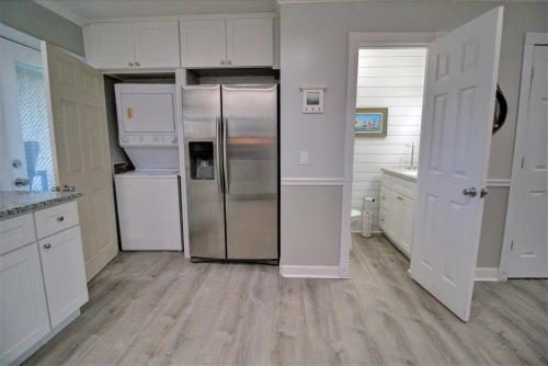 a kitchen with a stainless steel refrigerator and white cabinets at Living on the Edge Too in North Topsail Beach