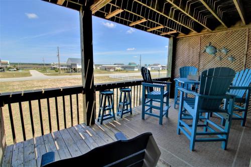 a porch with blue chairs and a table with a view at Living on the Edge Too in North Topsail Beach