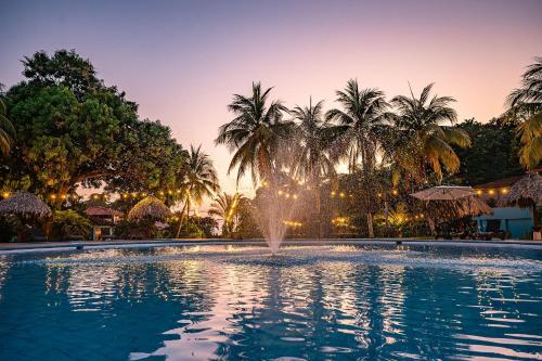 a fountain in the middle of a pool with palm trees at Beach Break Resort & CR Surf Camp in Jacó