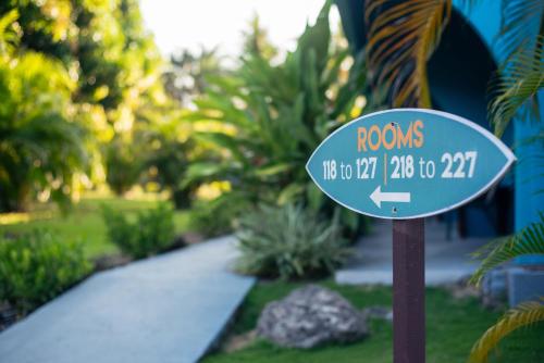 a blue street sign in a garden with an arrow at Beach Break Resort & CR Surf Camp in Jacó