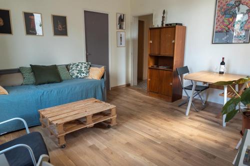 un salon avec un canapé bleu et une table dans l'établissement Confortable deux pièces aux portes de Paris, à Bagnolet