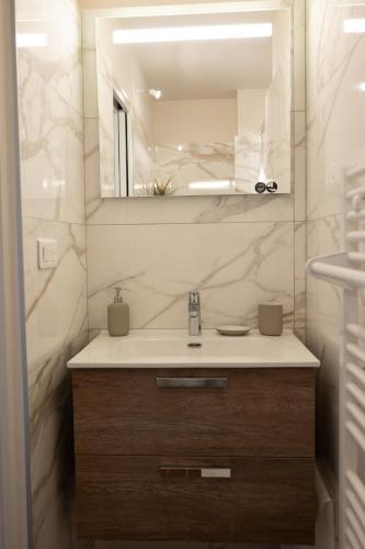 une salle de bain avec un lavabo et un miroir dans l'établissement Appartement Le grand Riche , vue sur les Alpilles, à Saint-Rémy-de-Provence