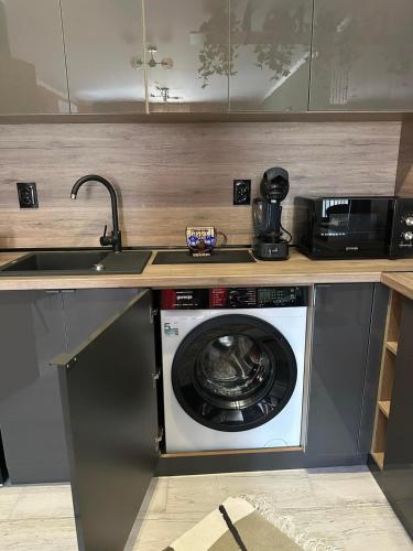a kitchen with a washing machine under a counter at Shtastliveca Guest Apartment in Velingrad