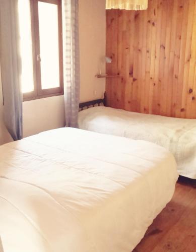 deux lits dans une chambre avec une fenêtre dans l'établissement La grangette, à Ajoux