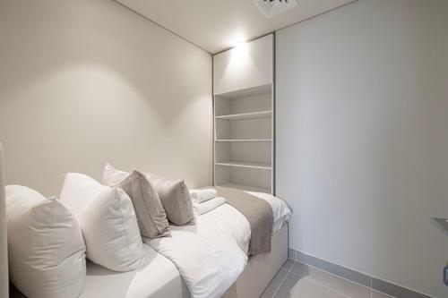 a bedroom with a bed with white sheets and pillows at Luxury 4BR Burj Khalifa & Fountain Views in Dubai