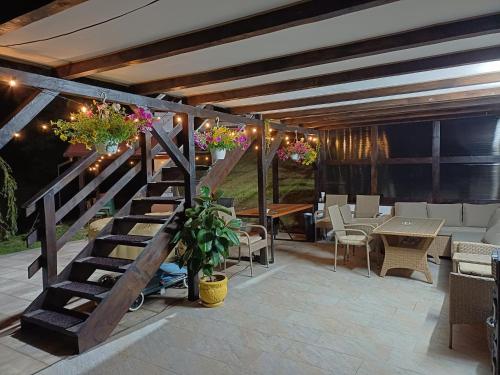 a patio with a wooden staircase and tables and chairs at Cabana Petersdorf in Petreşti