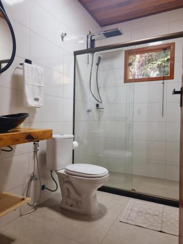 a bathroom with a toilet and a glass shower at Casa na Rampa - Hospedagem no Caravaggio in Santa Teresa