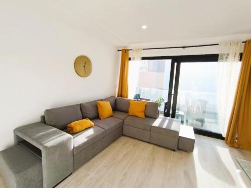 a living room with a gray couch with yellow pillows at Deluxe Arguineguin Beach in Arguineguín