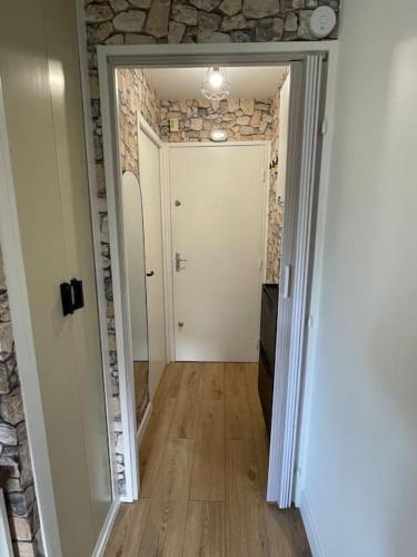 un couloir avec une porte blanche et un mur en pierre dans l'établissement Studio rénové 100m plage - Grand balcon - Parking, à Villers-sur-Mer