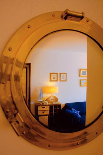 a mirror reflecting a room with a bed and a lamp at Cezimbra Guest House in Sesimbra