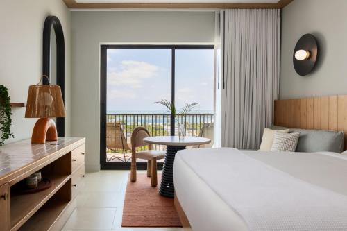 a bedroom with a bed and a table and a balcony at Hotel Indigo Grand Cayman by IHG in Grand Cayman