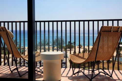 two chairs and a table on a balcony with the beach at Hotel Indigo Grand Cayman by IHG in Grand Cayman