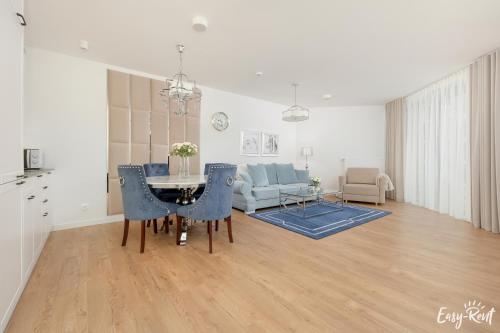 a living room with a table and blue chairs at Apartamenty Pinea z widokiem na morze Easy - Rent Apartments in Pobierowo