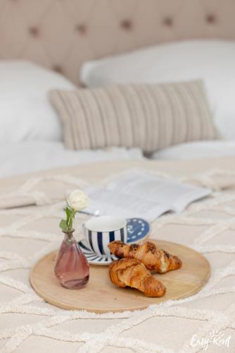 a tray of croissants and a cup of coffee on a bed at Apartamenty Pinea z widokiem na morze Easy - Rent Apartments in Pobierowo