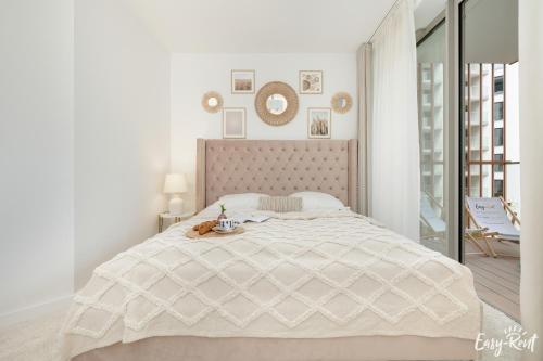 a white bedroom with a large bed and a balcony at Apartamenty Pinea z widokiem na morze Easy - Rent Apartments in Pobierowo