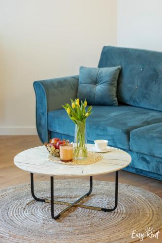 a coffee table with a vase of flowers on it at Apartamenty Pinea z widokiem na morze Easy - Rent Apartments in Pobierowo