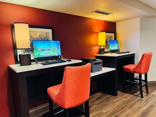 a room with two desks with a computer and orange chairs at Best Western Plus Stoneridge Inn & Conference Centre London Ontario in London