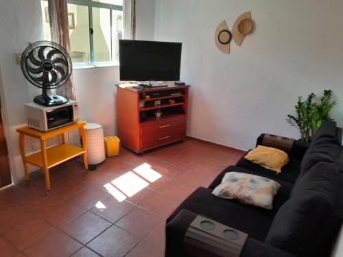 a living room with a couch and a television at Recanto São Sebastião in São Sebastião