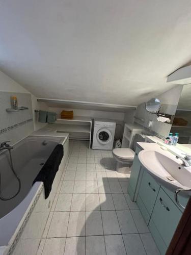 La salle de bains est pourvue d'une baignoire, d'un lavabo et d'un lave-linge. dans l'établissement Triplex T4 83m2 vue mer avec le patio et l'arrivée autonome, à Bandol