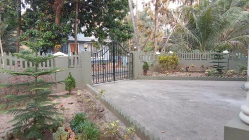 a white fence with a gate in a yard at Gonsalves villa in Arossim-Cansaulim