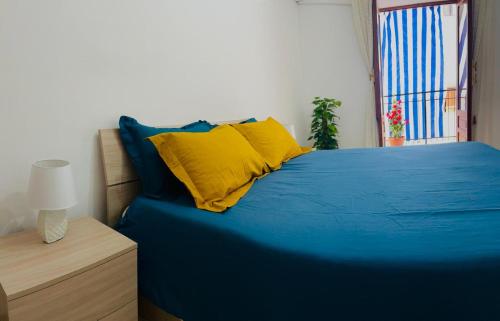 a blue bed with yellow pillows and a window at Casa Postierla SEA VIEW in Cefalù