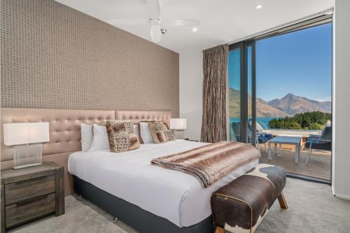 a bedroom with a large bed and a large window at Chic Central Penthouse & Spa by Staysouth in Queenstown