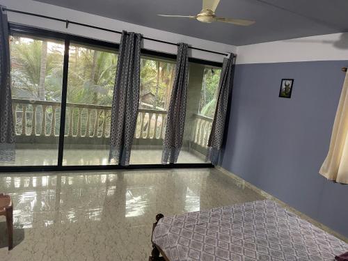 a bedroom with a bed and a large window at Gonsalves villa in Arossim-Cansaulim