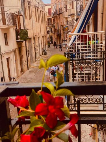 a vase with red flowers sitting on a balcony at Casa Postierla SEA VIEW in Cefalù
