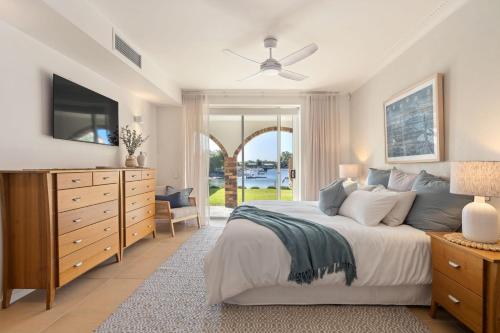 a bedroom with a bed with a dresser and a tv at Waterfront Bliss on Maroochydore Canal in Maroochydore