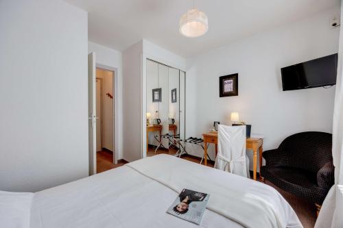 a bedroom with a bed and a table and a desk at Brit Hotel Confort Bagnoles Normandie in Bagnoles de l'Orne
