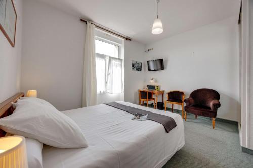 a bedroom with a bed and a desk and a window at Brit Hotel Confort Bagnoles Normandie in Bagnoles de l'Orne