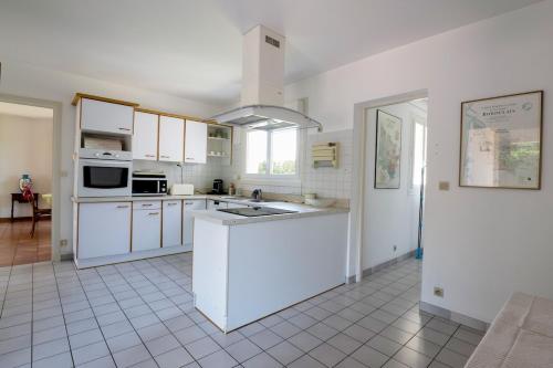 a kitchen with white cabinets and a white tile floor at Évasion à proximité de Bordeaux - Piscine Privée in Podensac