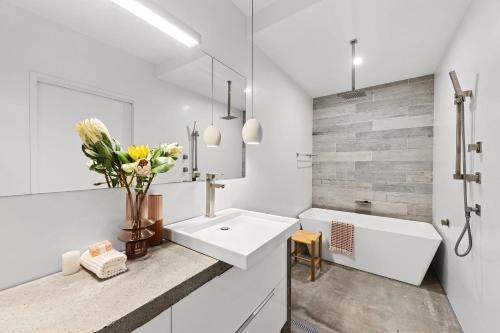 a white bathroom with a sink and a mirror at The Opal at Coolum - Mountain and Ocean Views in Yaroomba