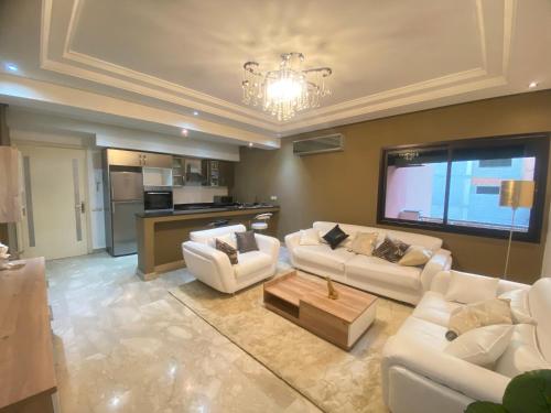 a living room with white couches and a kitchen at new and modern apartment in Marrakech