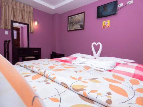 a bedroom with a bed with a pink wall at Hotel El Ejido in Quito